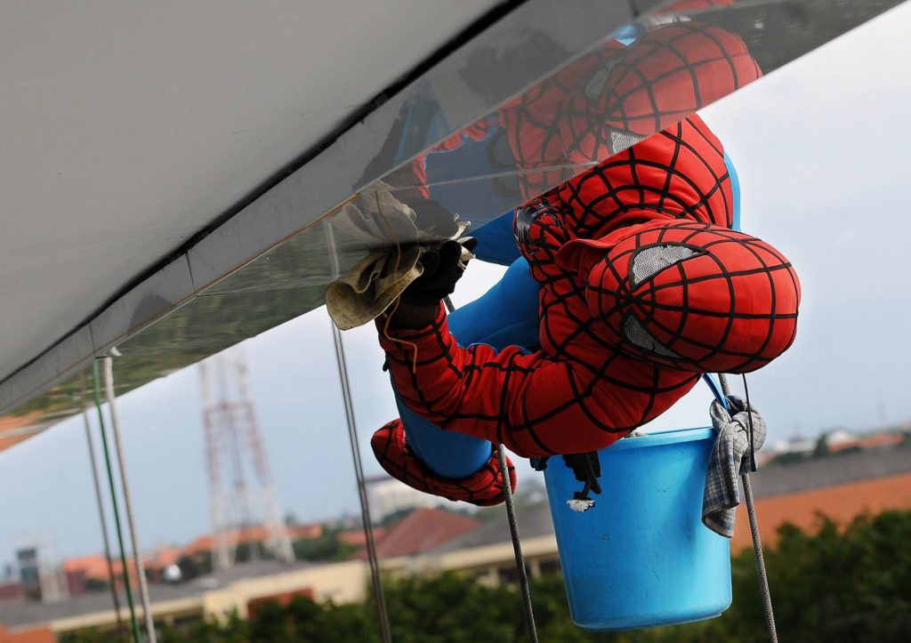 Image of someone dressed as Spiderman cleaning the windows